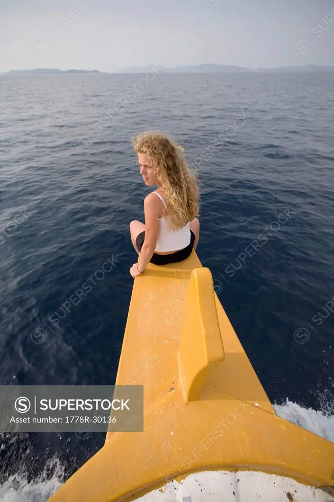 A teenage girl enjoys the sea breeze as she sits on the prow of a boat cruising the Adriatic Sea near Kornati National Park.