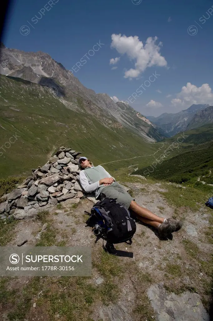 A teenage boy takes a cat nap against a pile of rocks in Vanoise National Park, French Alps.