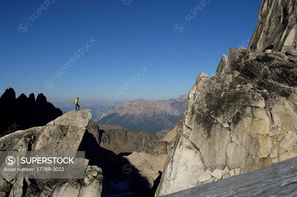 Male climber stands on granite summit.