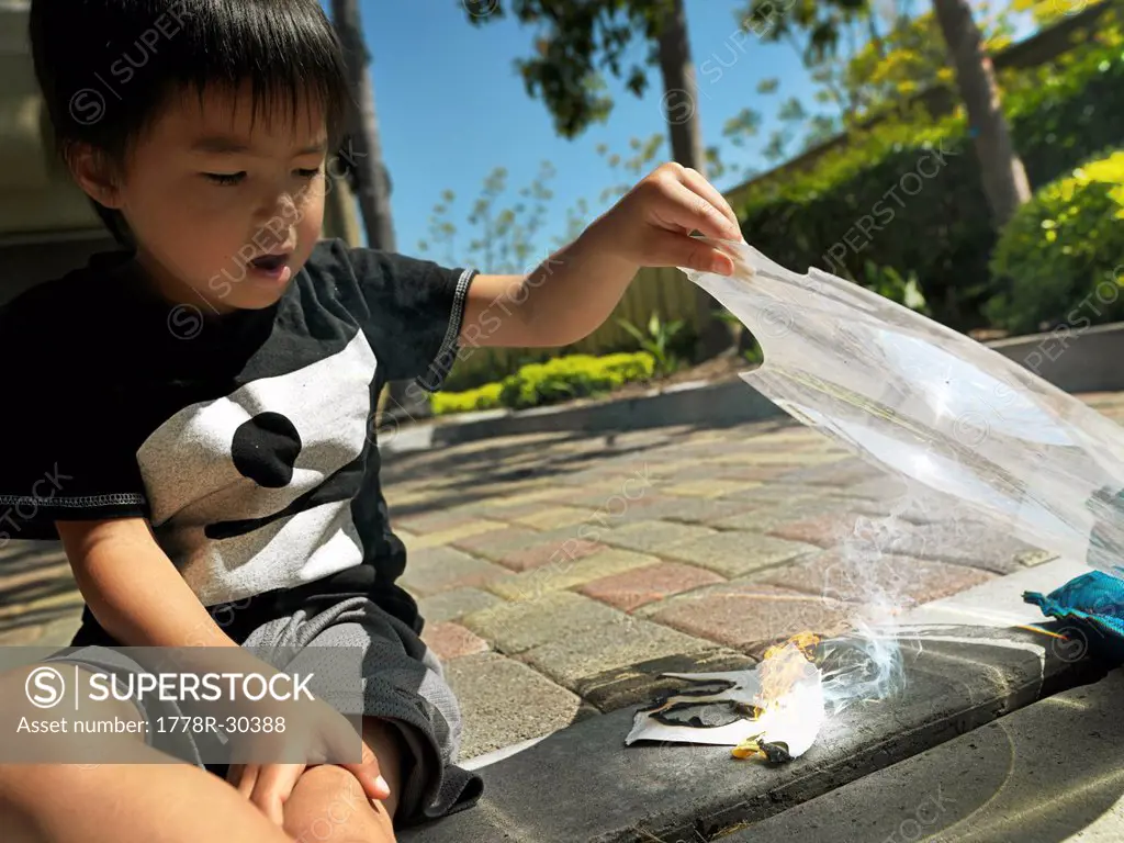 Kid making fire with a magnifying glass.