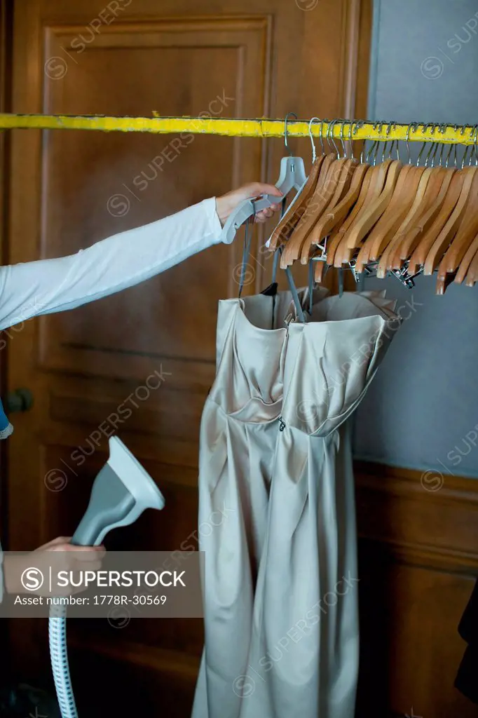 Woman cleaning two dresses.