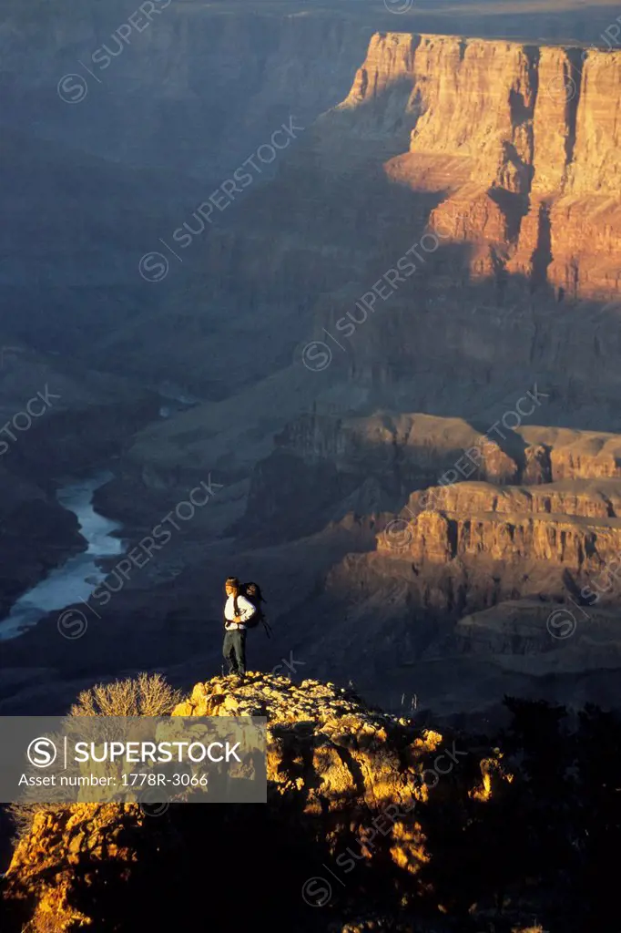Woman stands on rock at sunset in canyon.