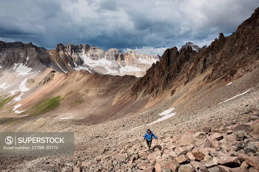 Female hiker ascending the rocky south slopes of Lavender Col route on Mt. Sneffels (14150 ft), San Juan mountains, Colorado, USA