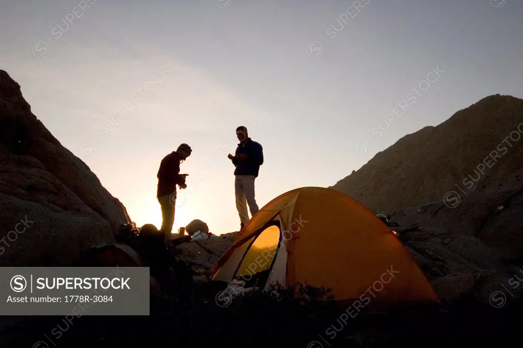 Two men stand outside tent.