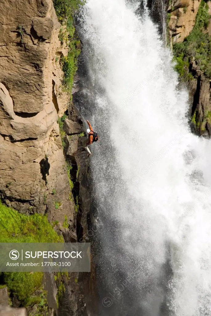 Climber rappels next to waterfall.