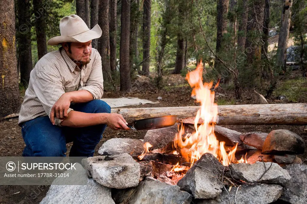 Cowboy cooking steak over a fire