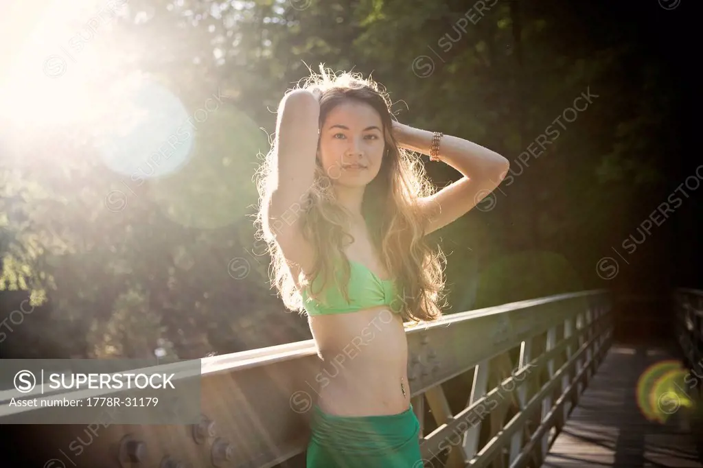A young asian woman in a bikini relaxes on a bridge on a hot day.