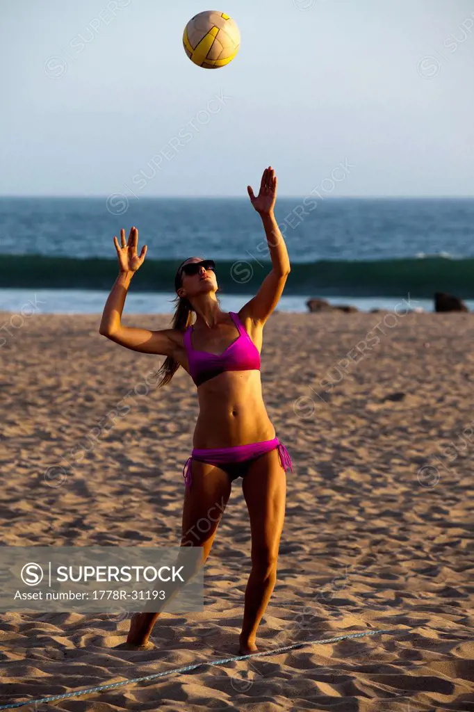 An athletic and toned female beach volleyball player sets up a serve during a match in Ventura, California.