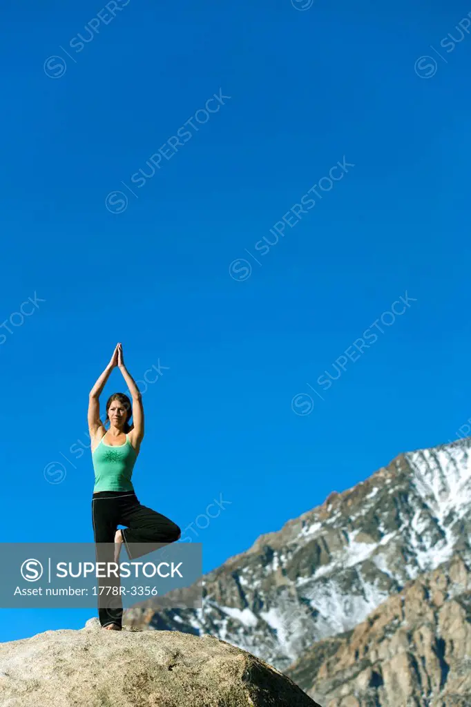 Woman doing yoga on boulder.