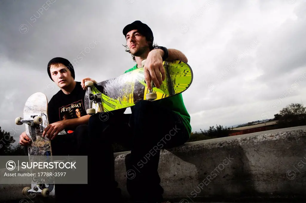 Two serious skateboarders sit for the camera.