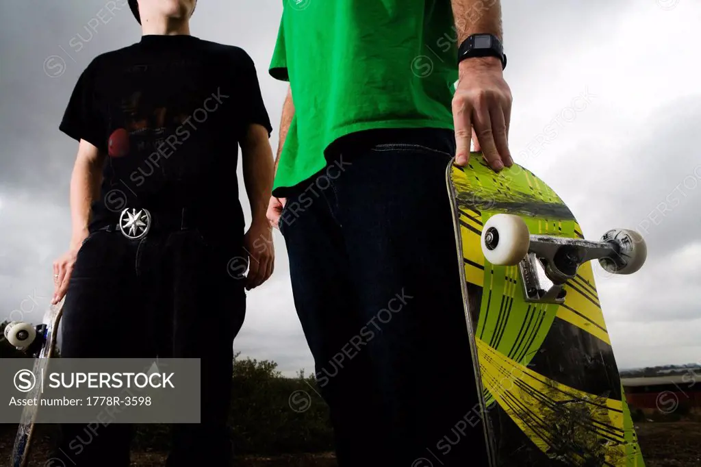 Two skateboarders shot low angle on mid section.