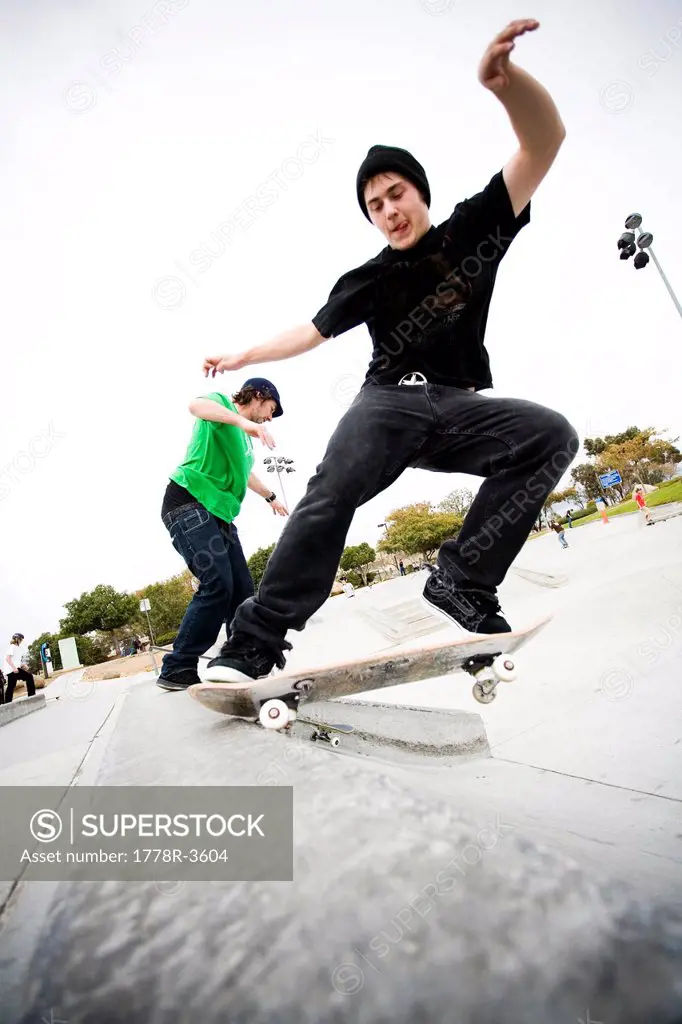 Two skateboarders do tricks at a skate park.