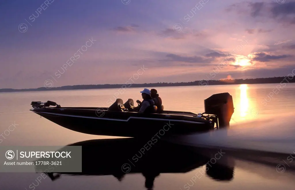 Men speed across open water in a boat.