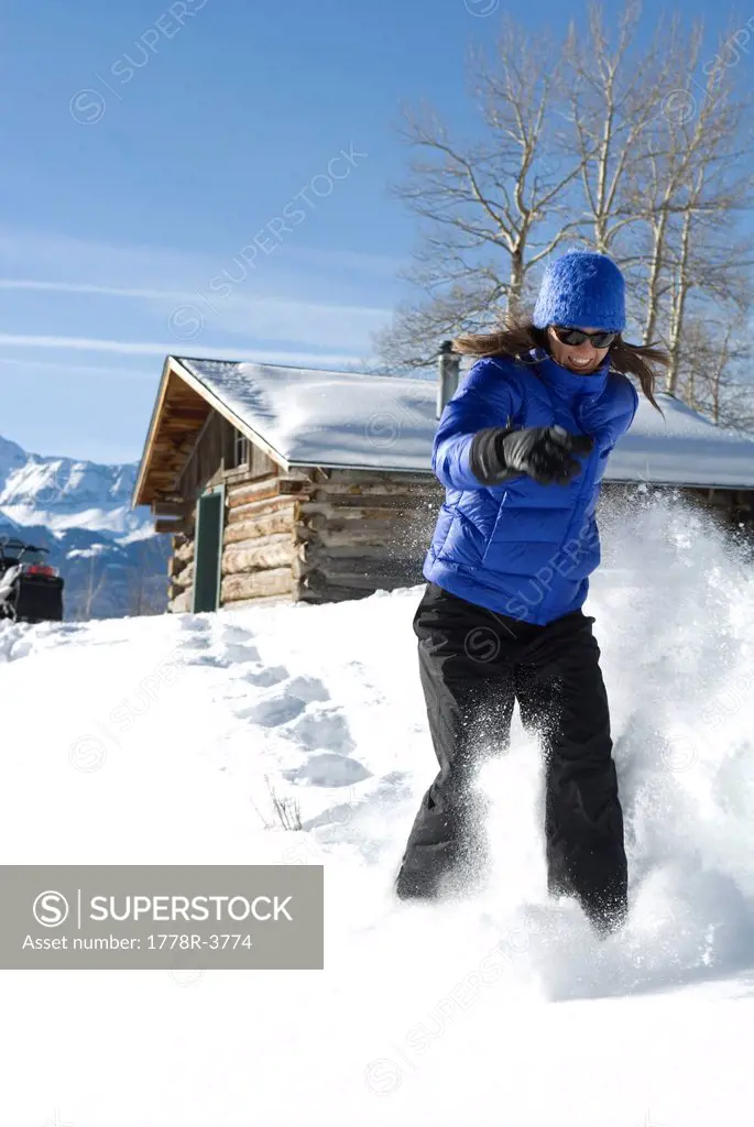 Woman snowshoeing outside cabin.