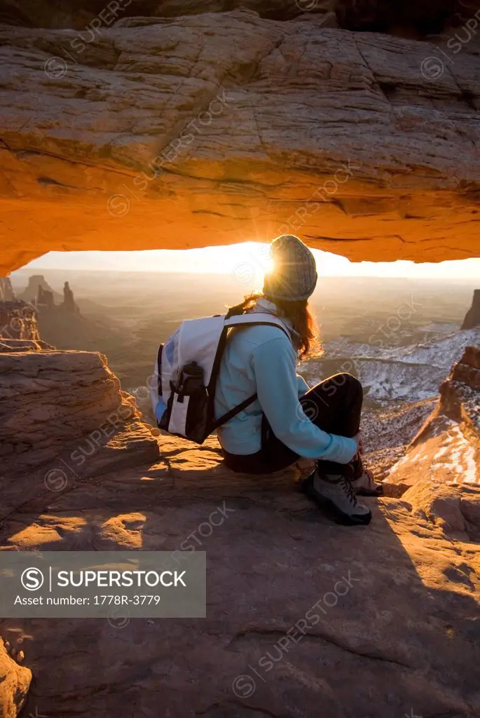 Woman sitting by rock arch.