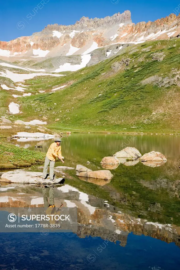 Man fishing in alpine lake.
