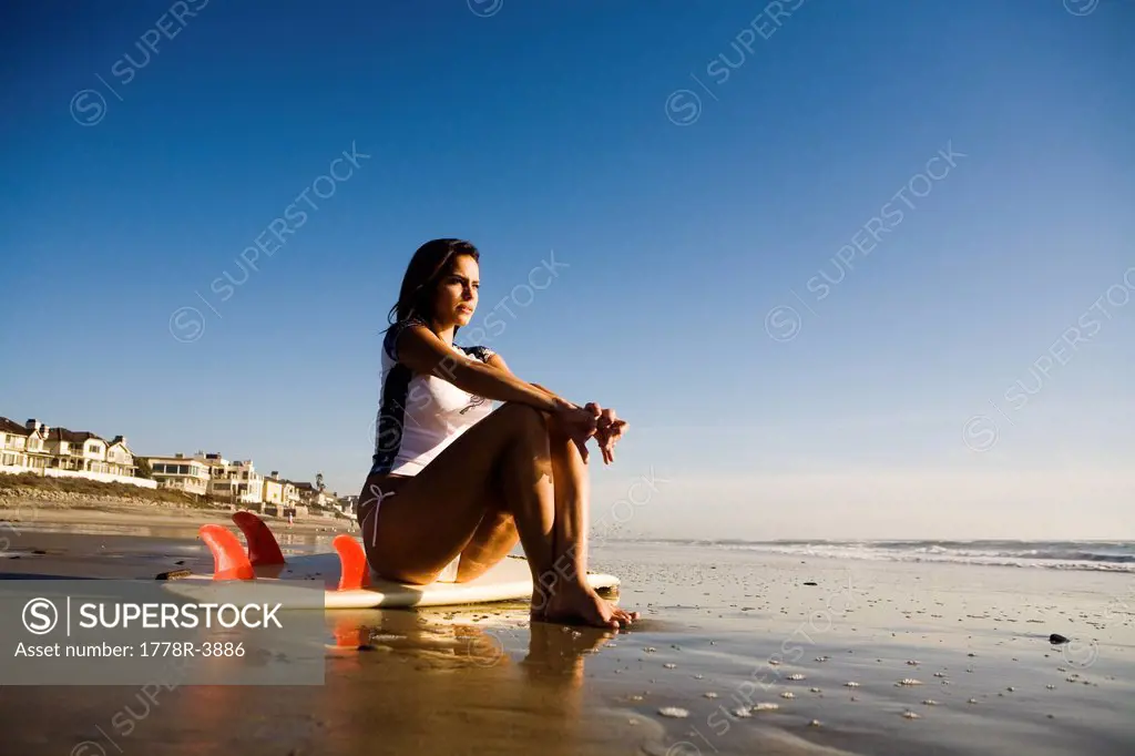 Young woman with surfboard on beach.