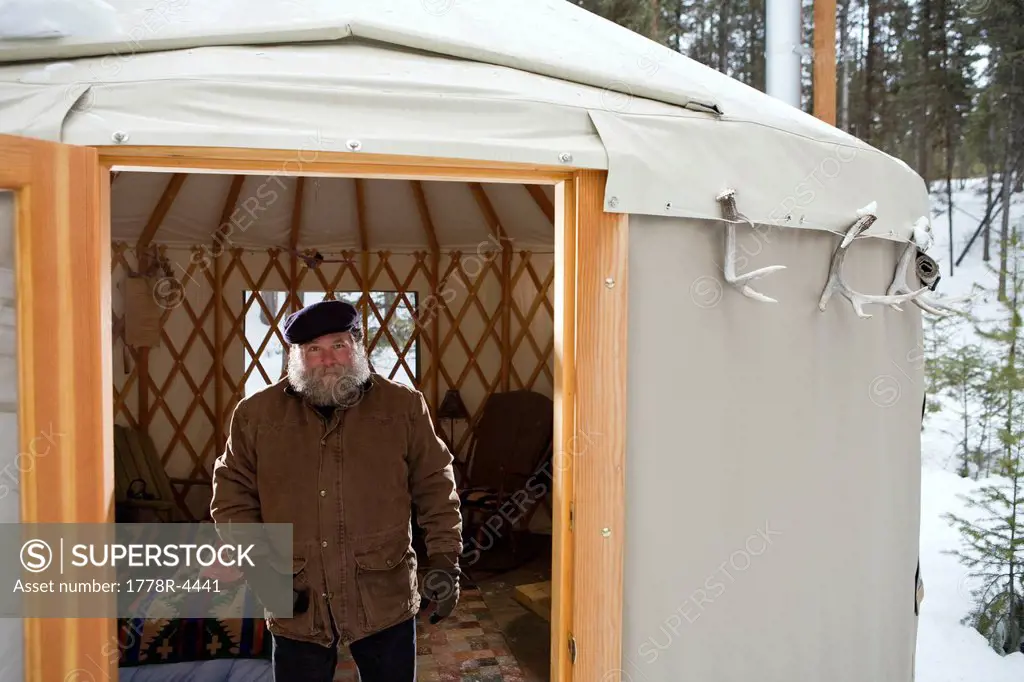 Bearded man with hat in sparse yurt, Whitefish, Montana.