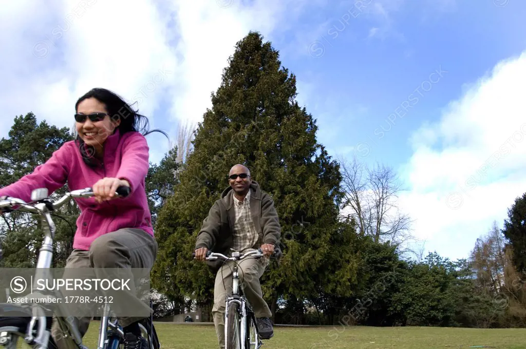 A young couple ride bikes on a sunny day.