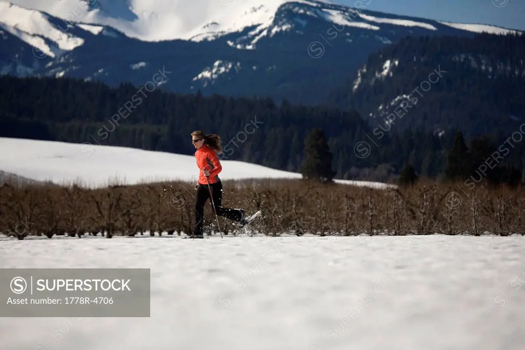 Young woman runs through snow with snowshoes near Mt. Hood, Oregon.