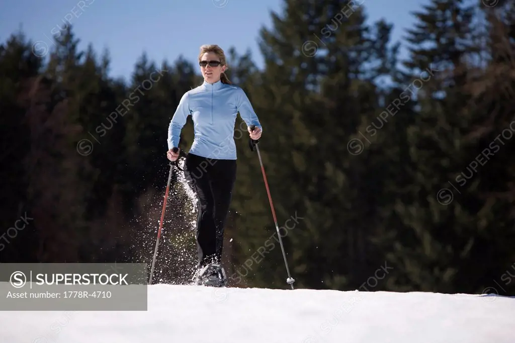 Young woman runs through snow with snowshoes near Mt. Hood, Oregon.