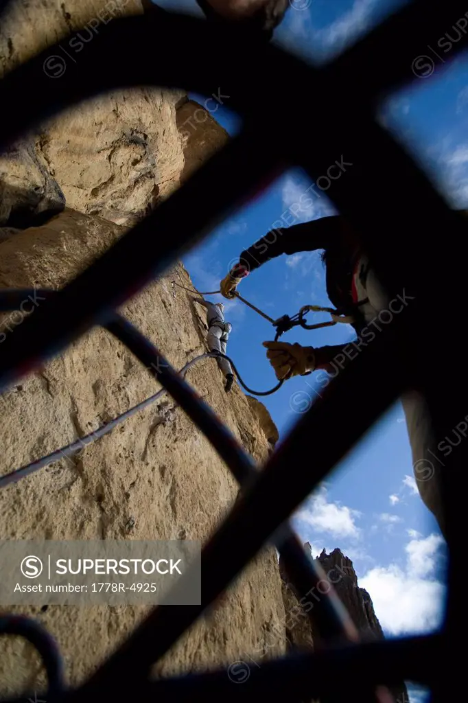 Peering up through a climbing rope at a belayer giving slack to a climber.