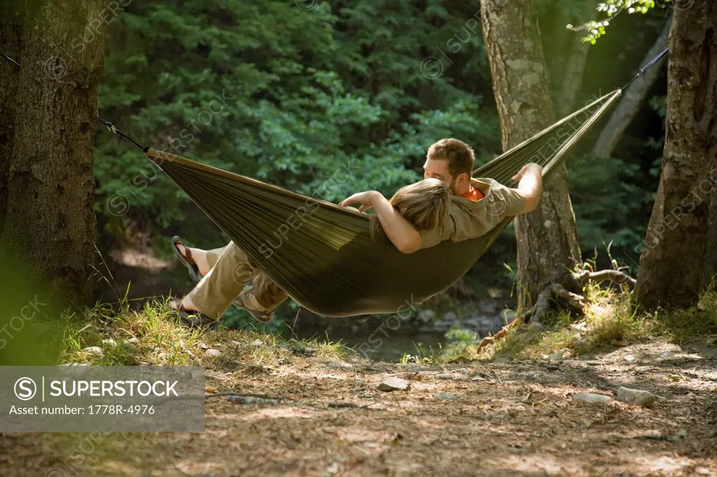 Couple relaxing in a hammock in the woods.