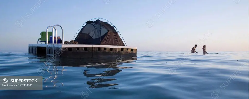 Couple camping on a floating platform in the ocean.