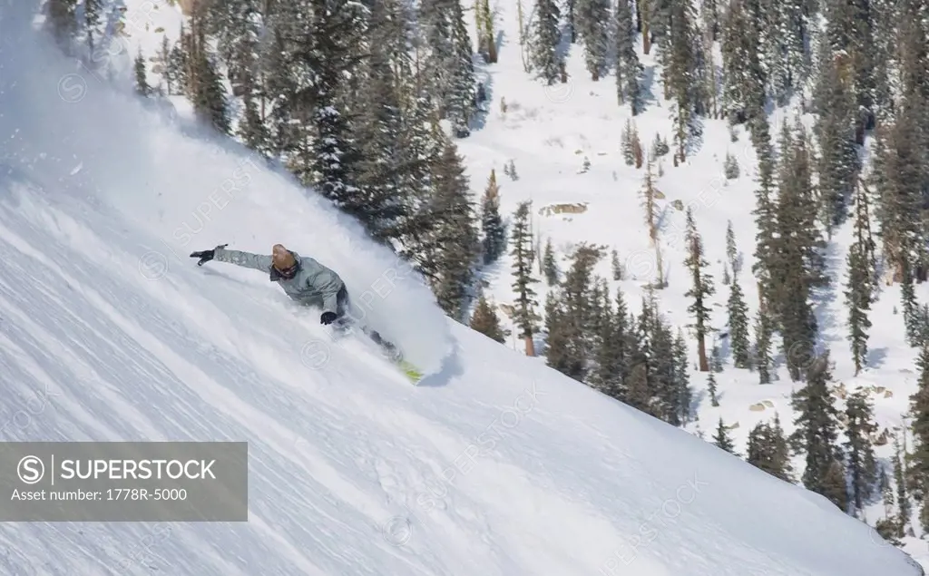 Snowboarder carving through powder snow.