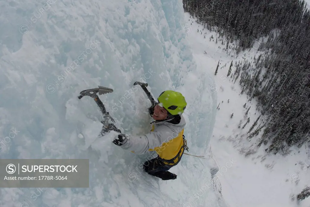 An ice climber ascending a frozen waterfall in the Canadian Rocky Mountains.