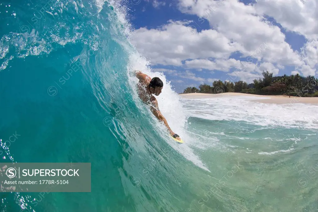 A young man body surfing at Keiki Beach on the North Shore of Oahu, Hawaii.