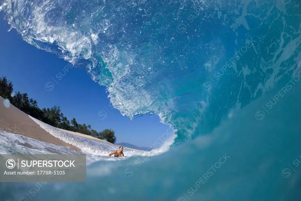 A young man about to be hit by wave at Keiki Beach on the North Shore of Oahu, Hawaii.