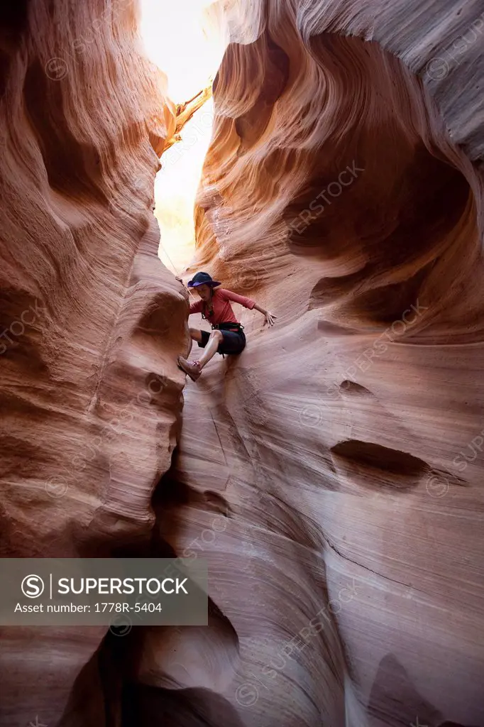A woman scrambles down a sculpted slot canyon in Utah.