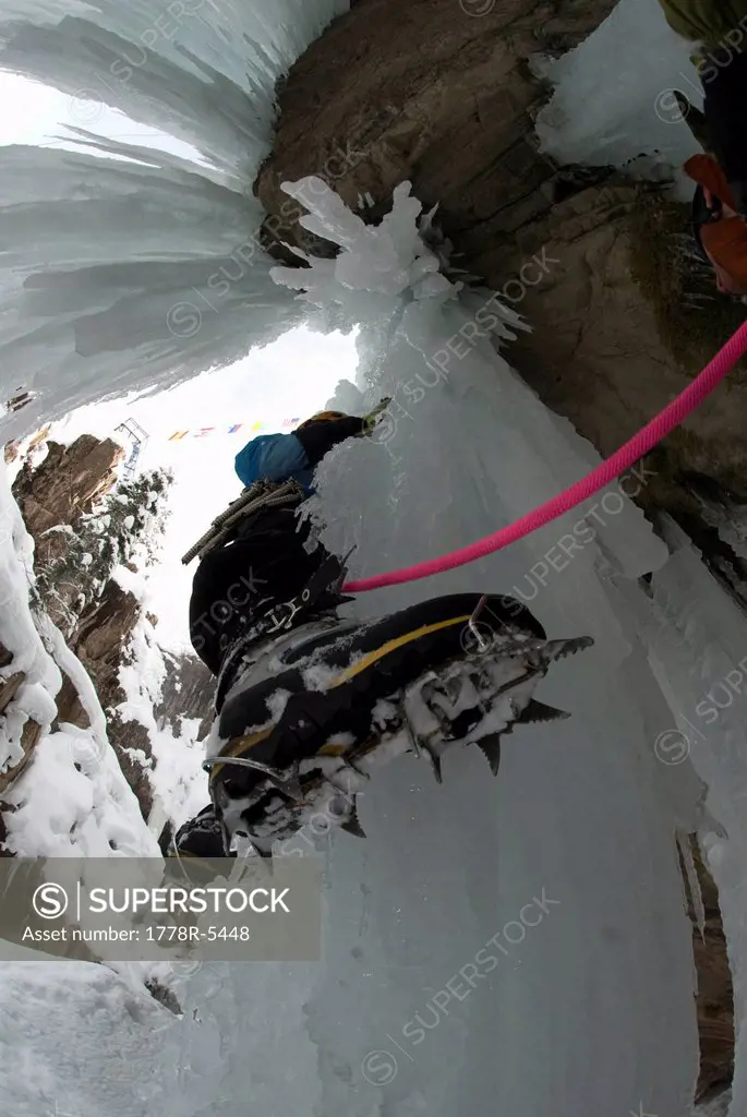 View of a woman´s boot and crampon from below while she is ice climbing a frozen waterfall.