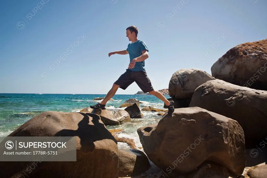 A man hops along boulders on the beach in The Baths National Park, Virgin Gorda, British Virgin Islands.