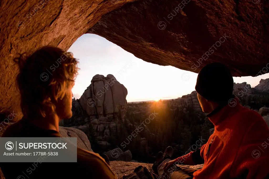 Two hikers enjoying a sunset from a rocky cliff at Vedauwoo, Wyoming.