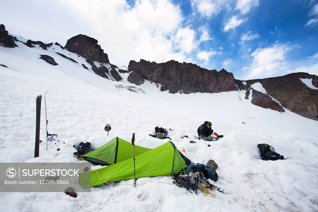 Two bivy sacks and skis indicate a campsite in the middle of snowfield..