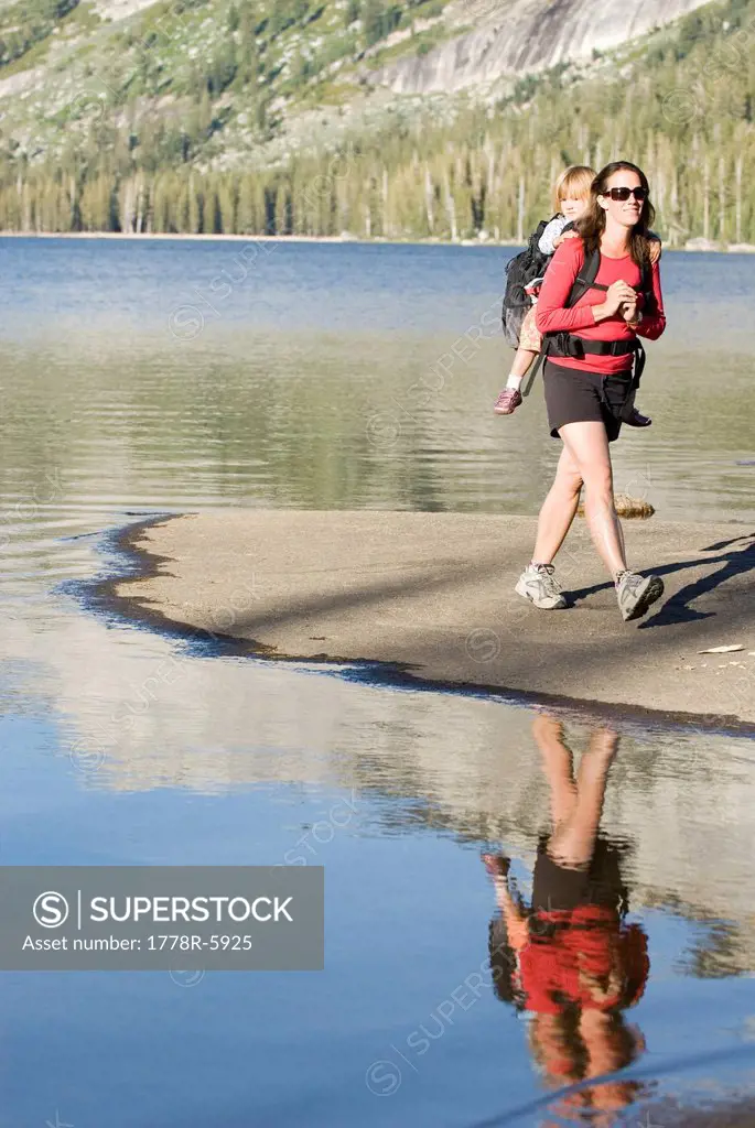 Woman and daughter walking on lake shore.