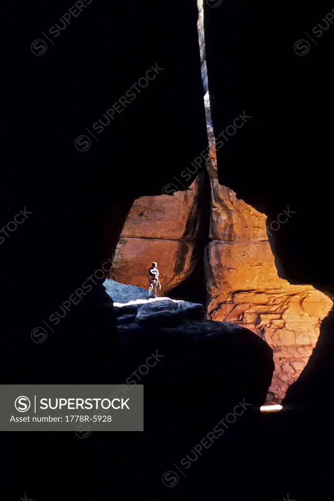 Man standing in rock crevasse.