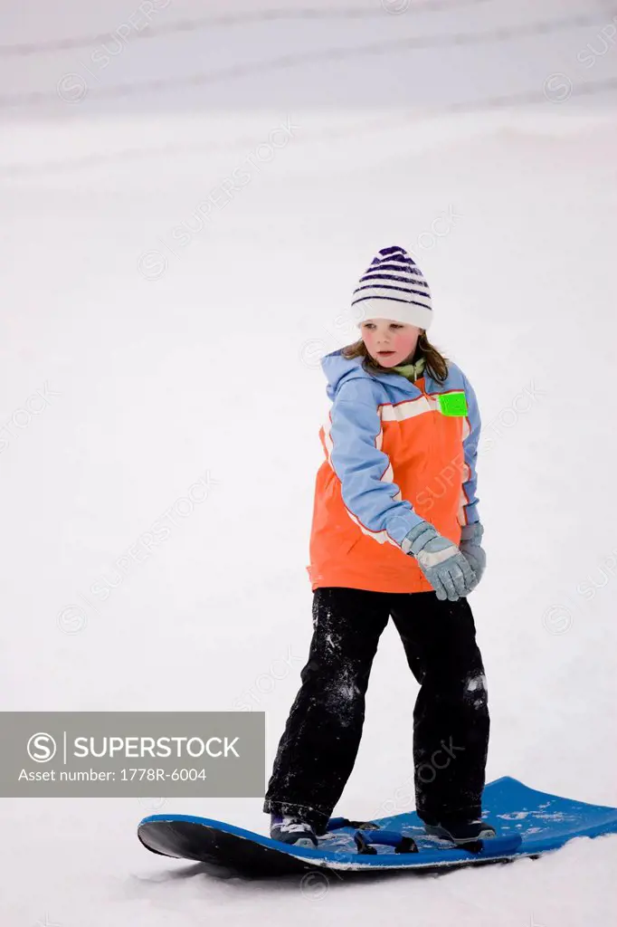 A young girl surfs on a snow sled in Dayton, Maine.