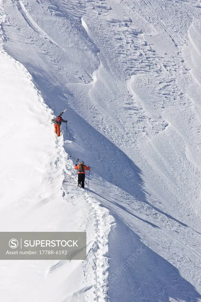 Two men hike up trail with skis to ski untracked powder off_piste in St. Anton am Arlberg, Austria.