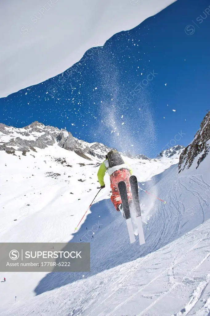A young man jumps off a cornice while skiing off_piste near St. Anton am Arlberg, Austria.
