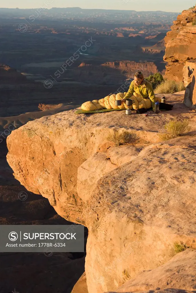 Woman camping on sandstone point, Canyonlands National Park, Utah.