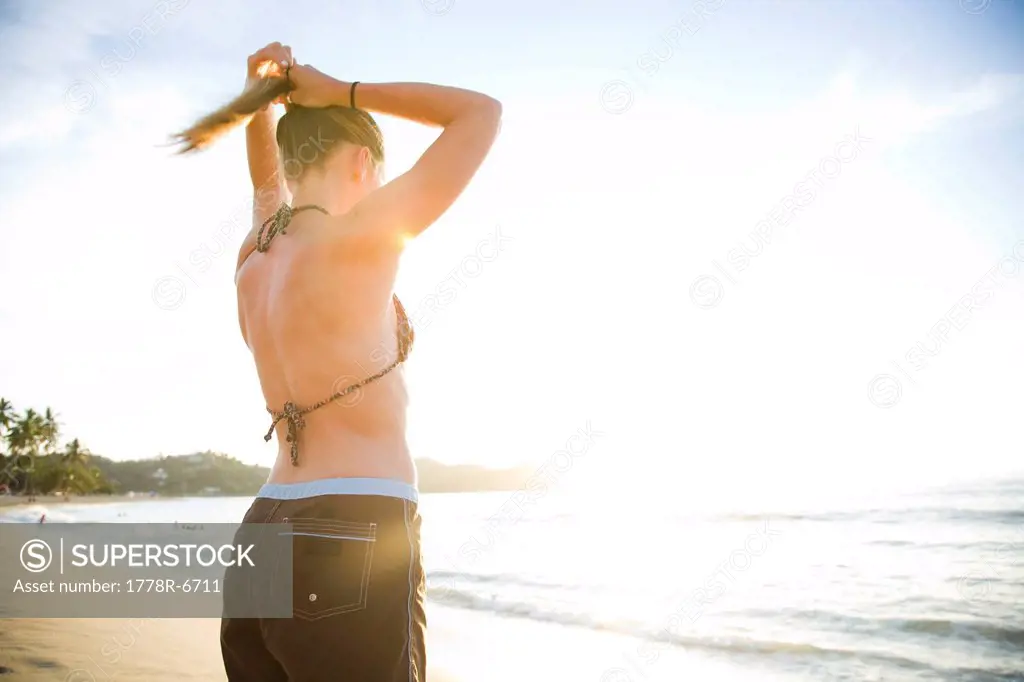 A young woman fixes her pony tail on a beach in Sayulita, Mexico.
