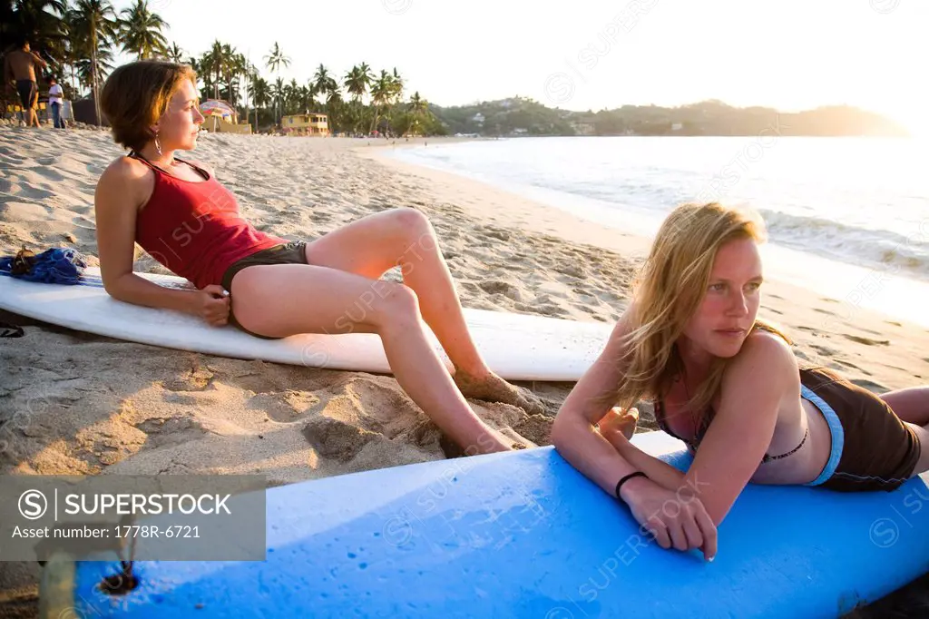 Two young girls sit on their surfboards after surfing near a remote beach in Sayulita, Mexico.