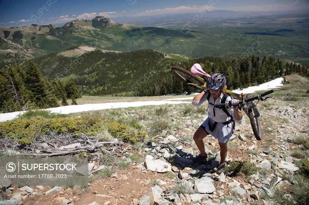 Woman carrying her bike on her shoulders in the Abajo Mountains near Montecello, Utah.