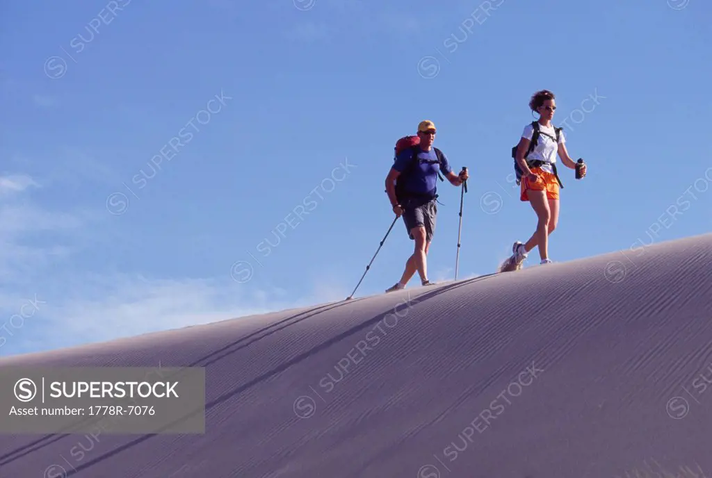 Couple backpacking or fastpacking on dunes along the Oregon coast.