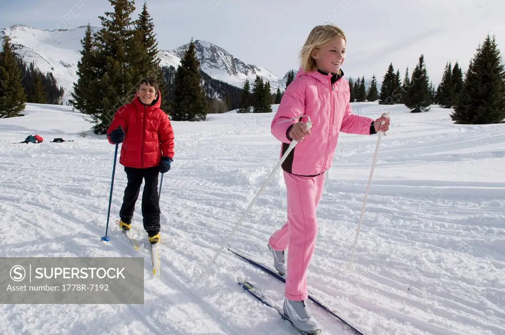 A young girl and boy cross country skiing in the San Juan National Forest, Colorado.