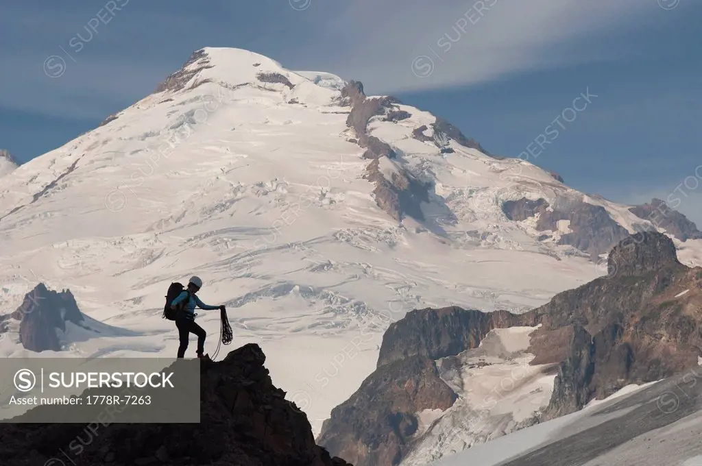 A woman mountaineer standing on pinnacle below Mount Baker, Mount Baker Wilderness, Bellingham, Washington.