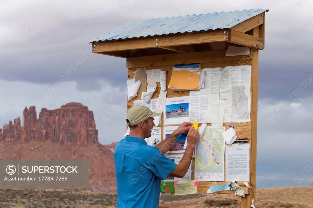 A hiker posting a message on a board at a trailhead, Indian Creek, Monticello, Utah.